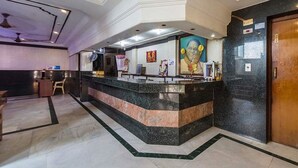 A reception area with a marble counter, a wooden door, and a wall with religious artwork.