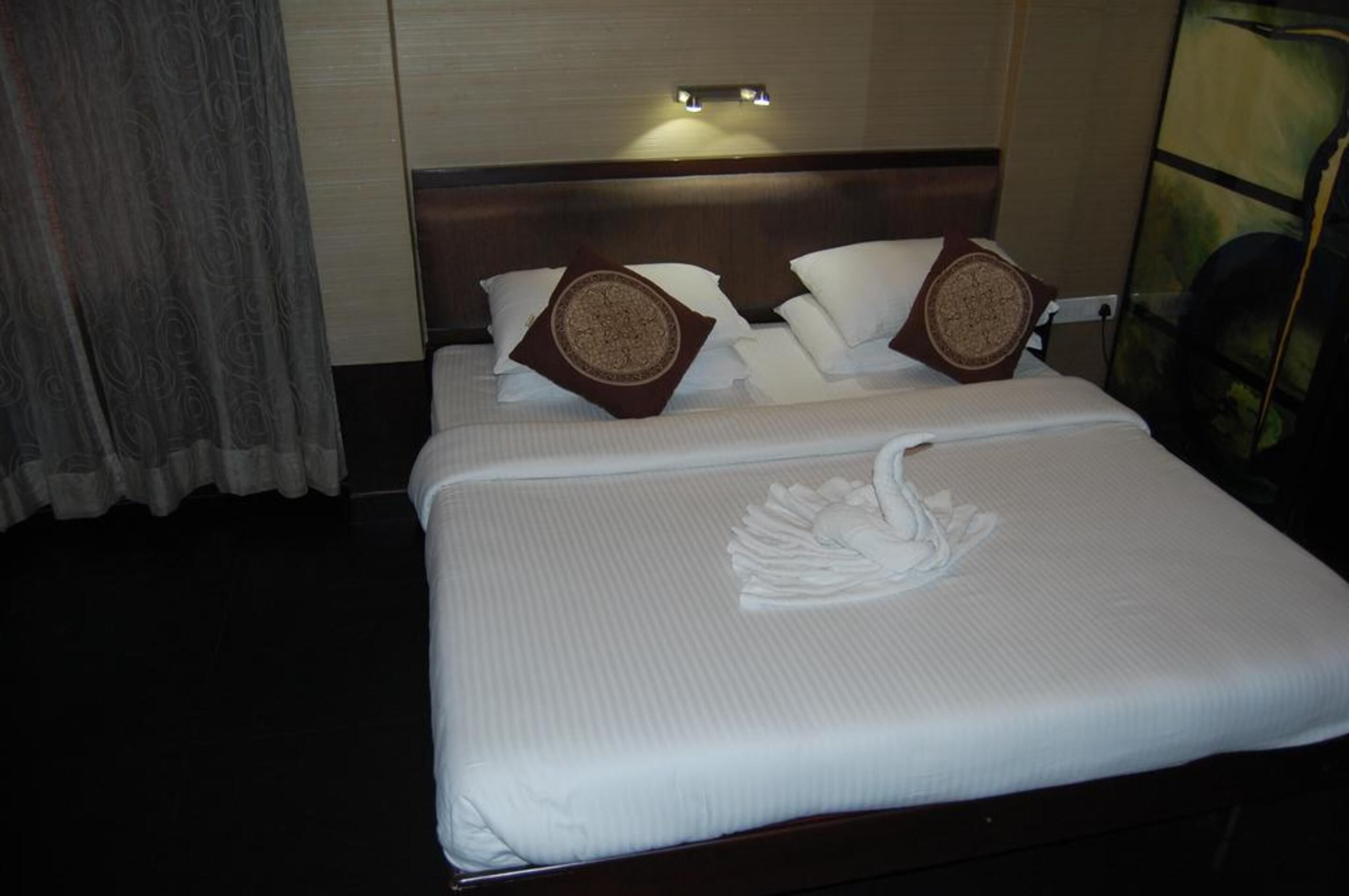 A neatly made bed with a decorative swan design, a wooden headboard, and two decorative pillows.