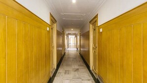 A long, narrow hallway with wooden paneling on both sides and a marble floor.