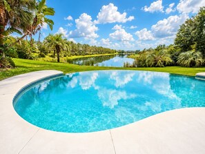 A swimming pool with a curved edge, surrounded by a well-maintained lawn and palm trees. - SWISS 66 - Lake Denise (Clermont)