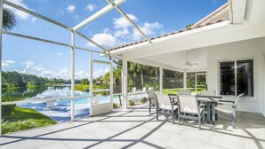 Une terrasse couverte avec vue sur un lac, des sièges d’extérieur et un ventilateur de plafond.