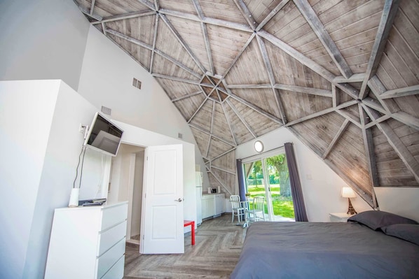 Une chambre avec un plafond en pente, un lit, un bureau et une chaise.