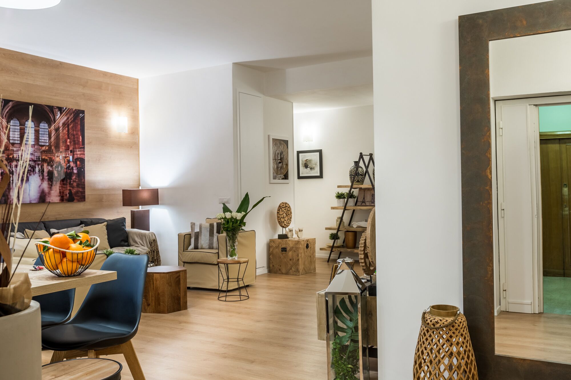 A modern living room with a wooden floor, a dining area with a table and chairs, and a large painting on the wall.