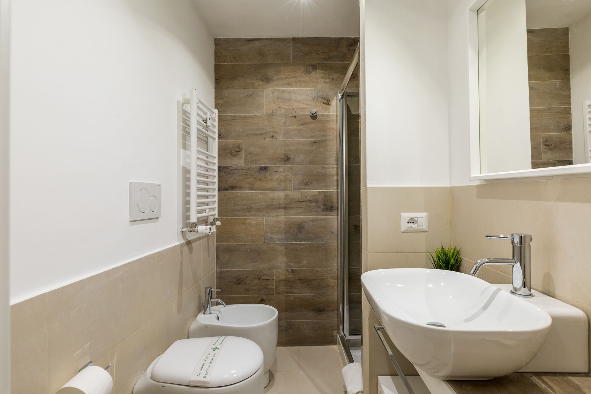 A modern bathroom with a shower, toilet, bidet, and sink.