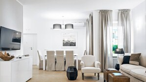 A modern living room with a flat-screen TV, a dining area with a table and chairs, a sofa, and a coffee table. - The Best in Rome Vite (Rome)