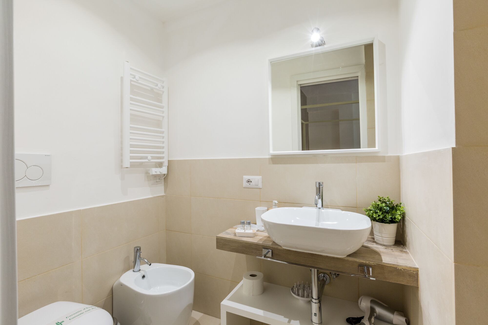 Un baño con un lavamanos blanco, un espejo encima y un inodoro.