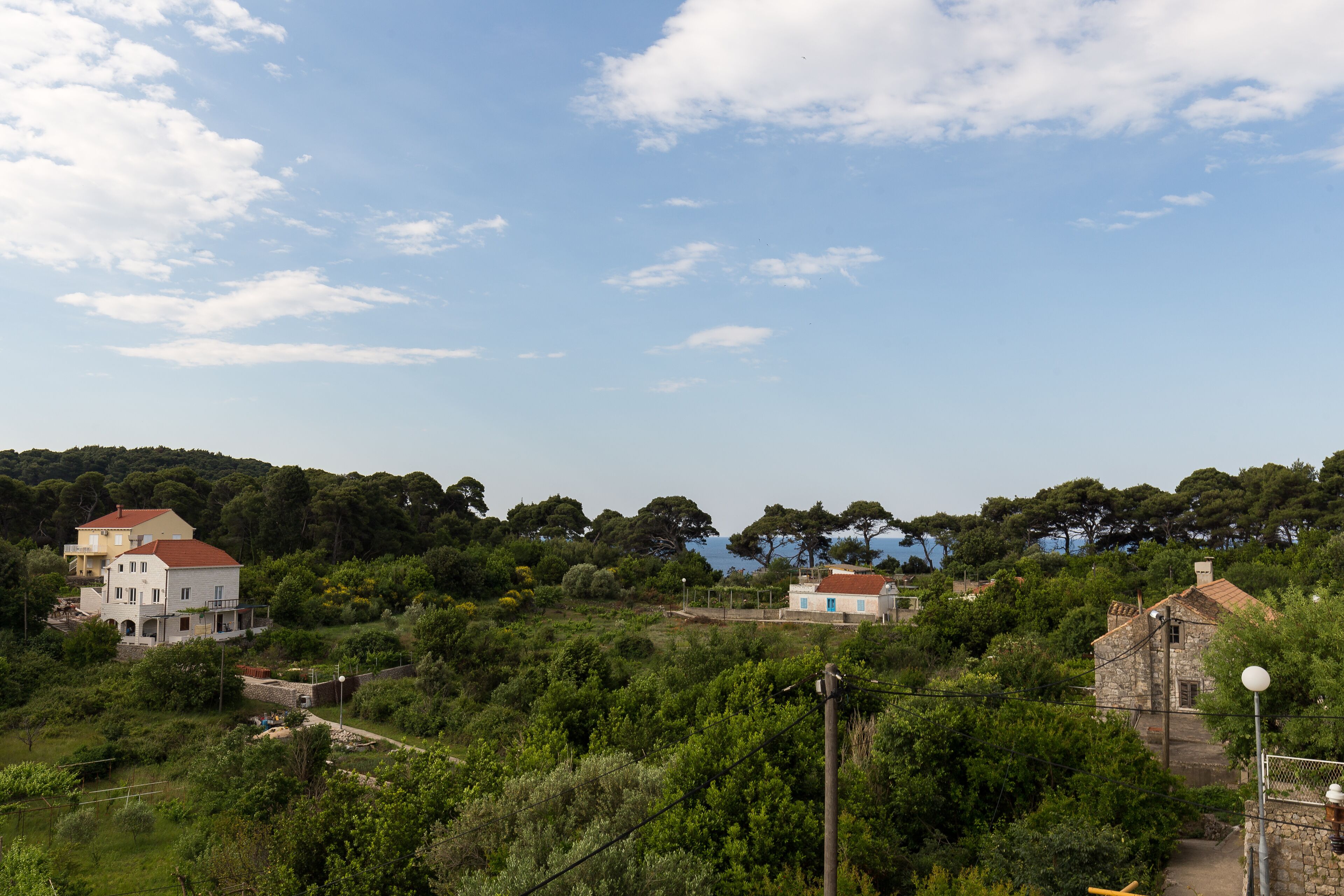 Un pueblo costero con edificios de piedra tradicionales, abundante vegetación y cielo despejado.