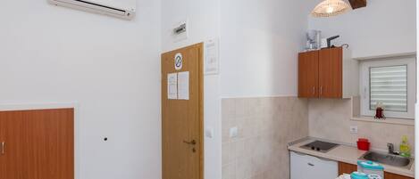 Eine kompakte Küche mit Spüle, kleinem Kühlschrank und Holzschränken.