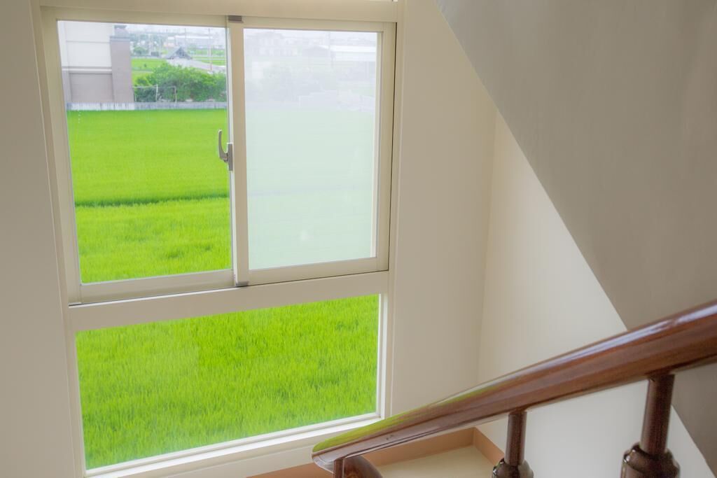 A room with a view of a green field through a window.