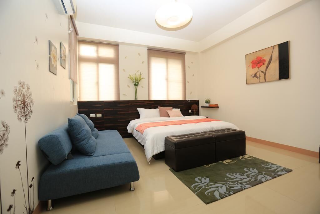Une chambre à coucher moderne avec un lit, un canapé bleu, une petite table et une plante décorative.