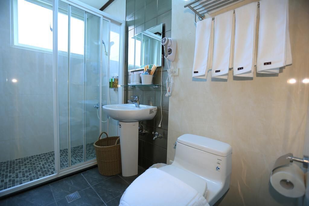 A modern bathroom with a glass shower enclosure, a sink, a toilet, and a towel rack.