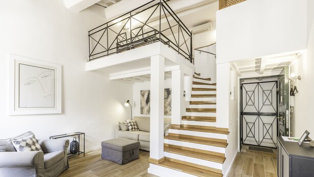 Uma sala de estar ampla com teto alto, escada e design moderno.