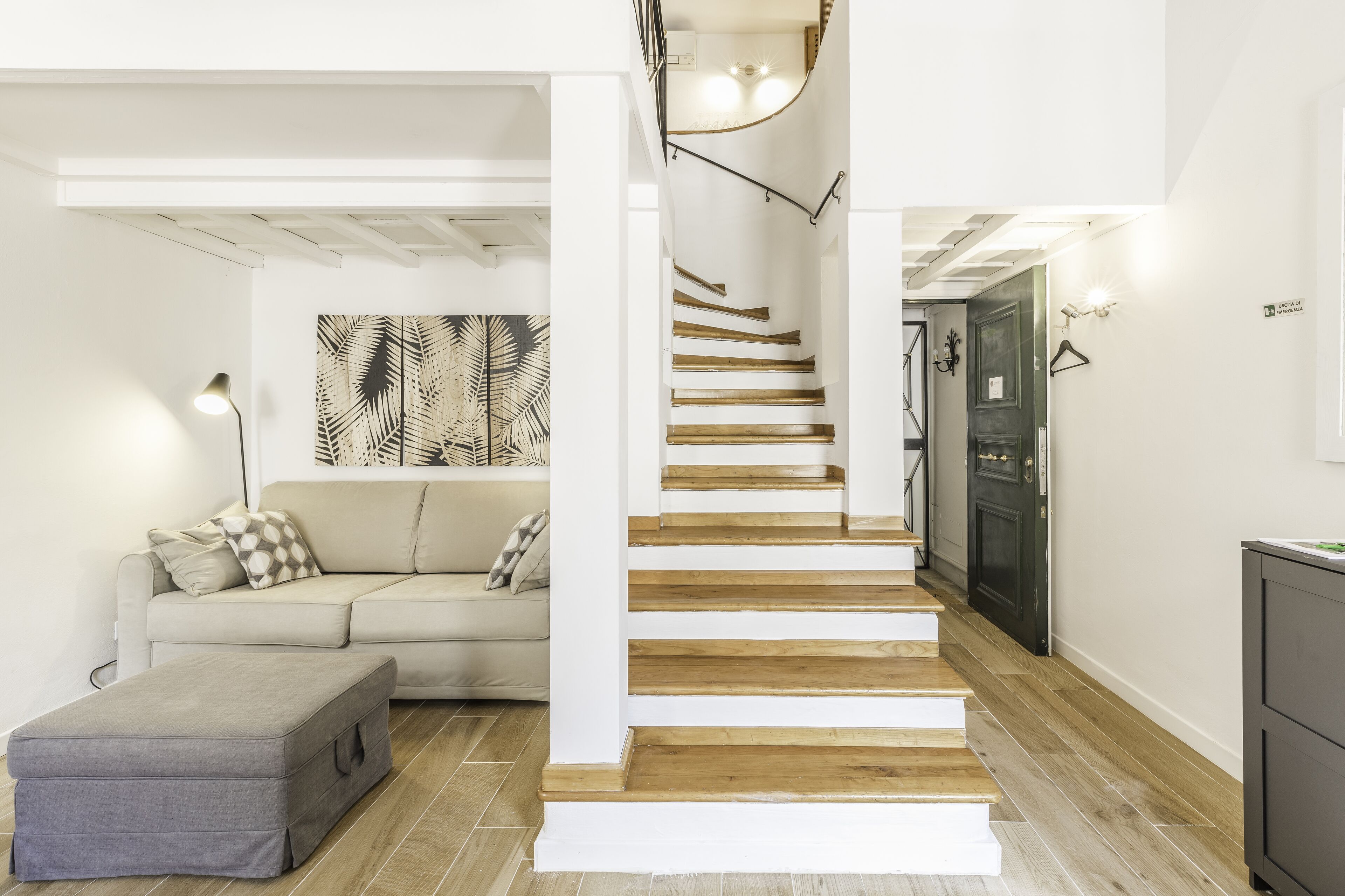 A modern interior with a staircase, a sofa, and a cabinet.