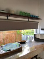 Cocina con cerca de bambú, microondas y ventana con vista a follaje.