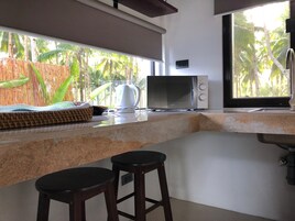 Una cocina equipada con microondas, hervidor y taburetes de bar.