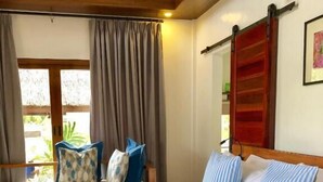 A neatly made bed with striped bedding and pillows, a wooden headboard, and a window with curtains. - The Village Siargao (General Luna)