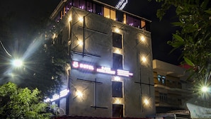 A building with multiple windows and a neon sign indicating a hotel. - Treebo Tryst F One (Hyderabad)