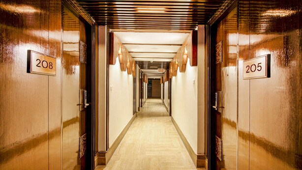 A hotel corridor with doors numbered 205 and 208, featuring a wooden floor and a ceiling with horizontal slats. - Treebo Tryst F One (Hyderabad)