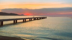 Un muelle se adentra en aguas tranquilas al atardecer, bajo un cielo despejado.
