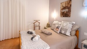 Un dormitorio con cama, almohadas, una colcha, una lámpara colgante y una obra de arte en la pared.
