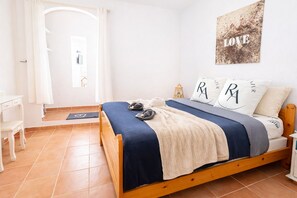 Un dormitorio con una cama de madera, una mesita de noche, una lámpara de noche, una obra de arte en la pared y vistas al exterior.