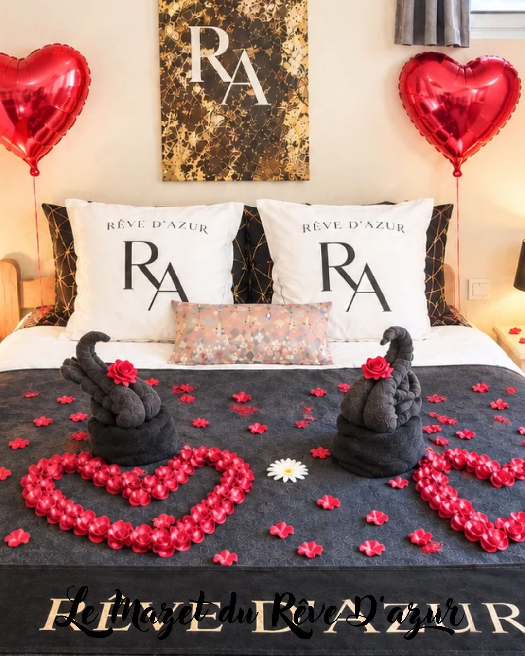 A bed with two pillows, a decorative pillow, and a heart-shaped arrangement of flowers and swans on the bedspread.