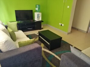 En stue med en sofa, et sofabord, et fjernsyn og en vanddispenser.