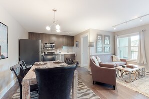 Enjoy meals in the central dining area with a wooden table and comfortable chairs, or relax in the adjacent seating area with a sofa and coffee table.