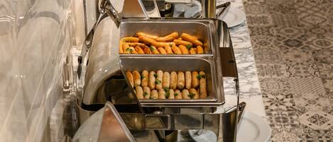 Una barra de buffet con diversas opciones de comida, incluyendo tocino, salchichas y otras carnes.