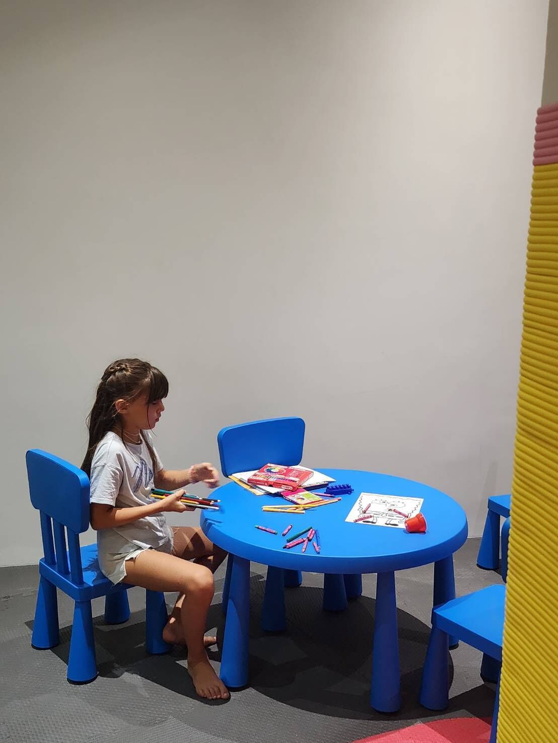 A child sitting at a blue table with various art supplies.