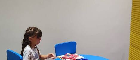 A child sitting at a blue table with various art supplies.