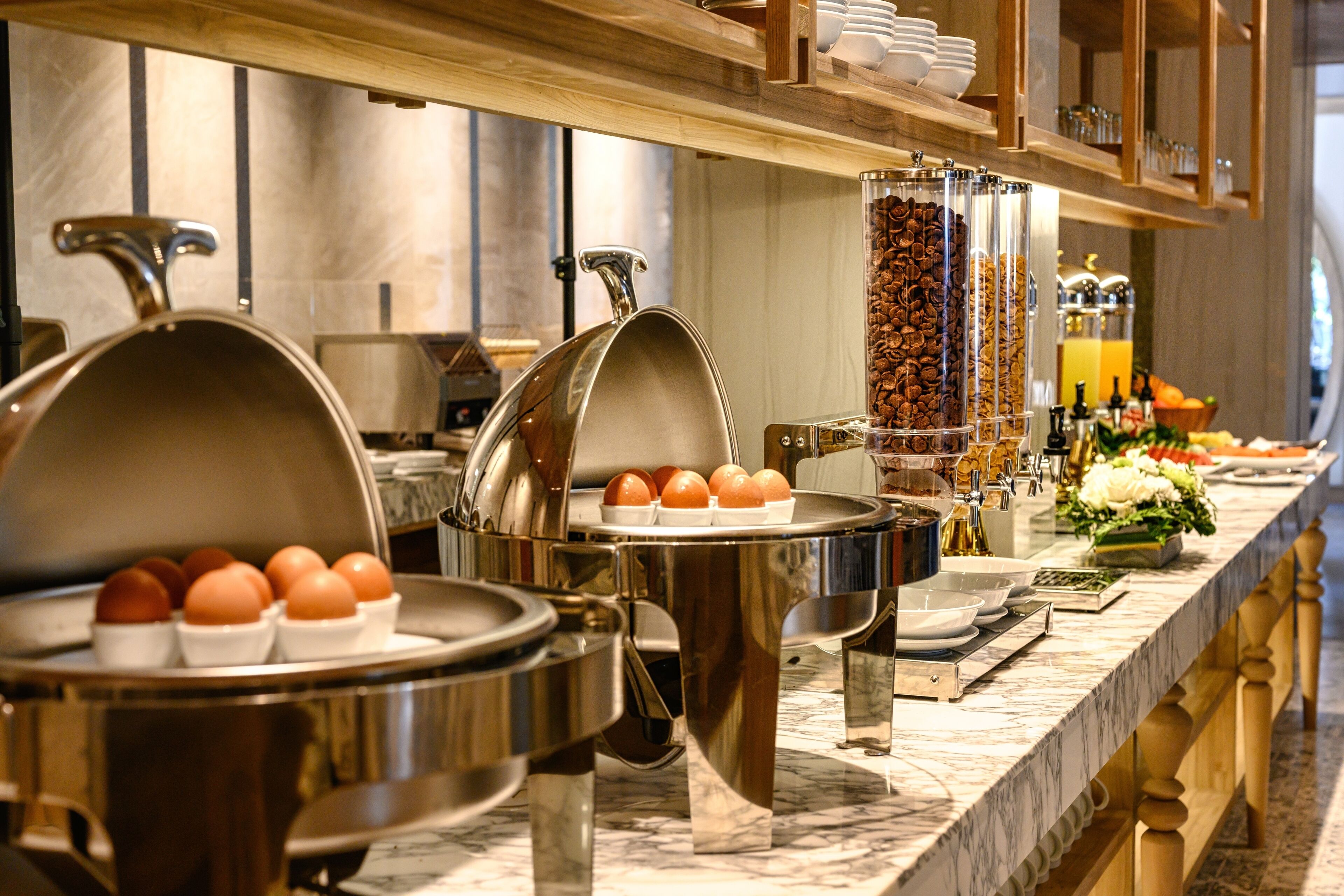 A buffet setup with various food stations, including a coffee dispenser and a fruit display.