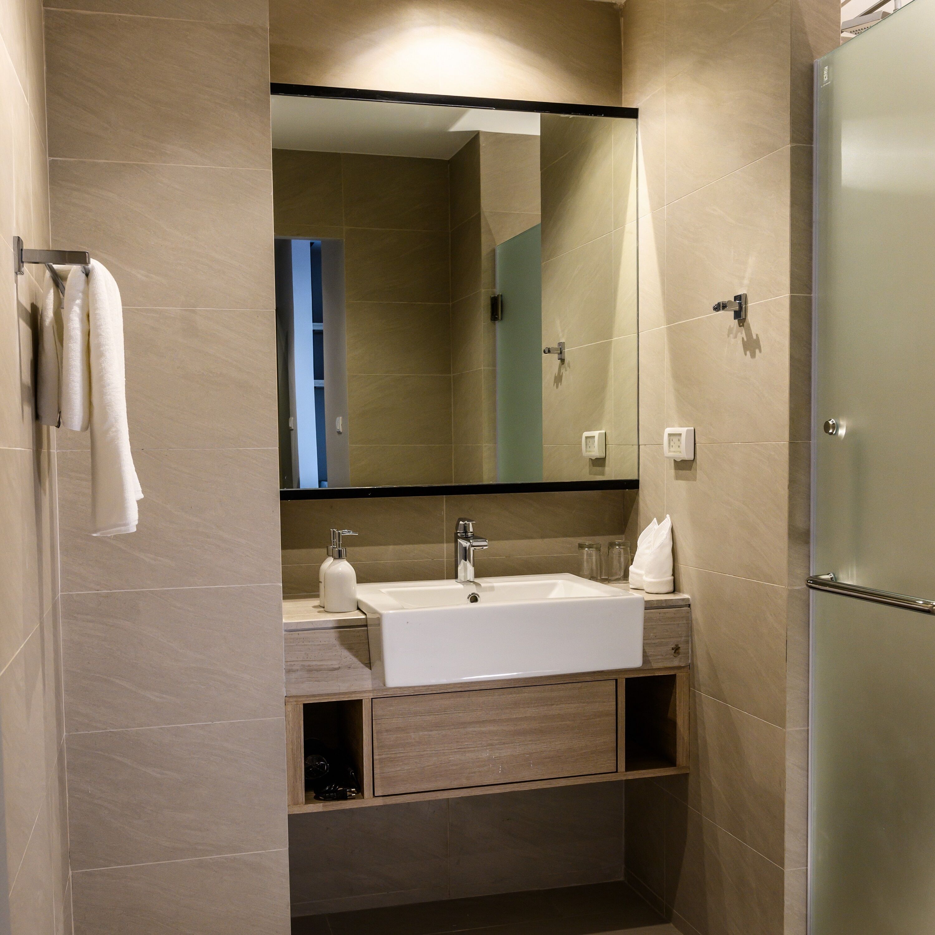 A modern bathroom with a large mirror, a sink, and a shower.