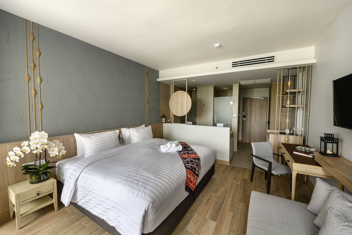 Una habitación de hotel moderna con una cama grande, una mesita de noche y un escritorio con una silla.