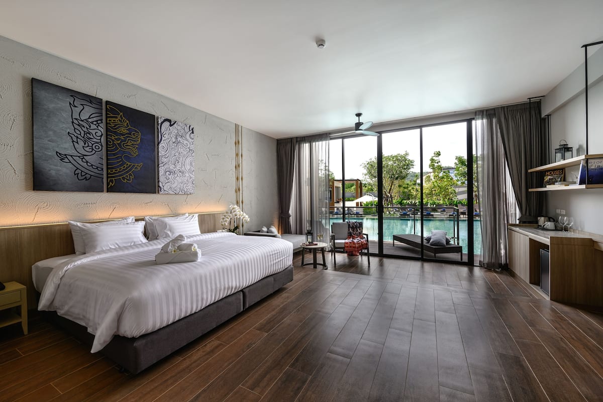 Una habitación de hotel moderna con una cama grande, vista a una piscina y un balcón.