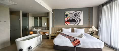 A modern hotel room with a large bed, a bathtub, and a bathroom with a mirror and sink.