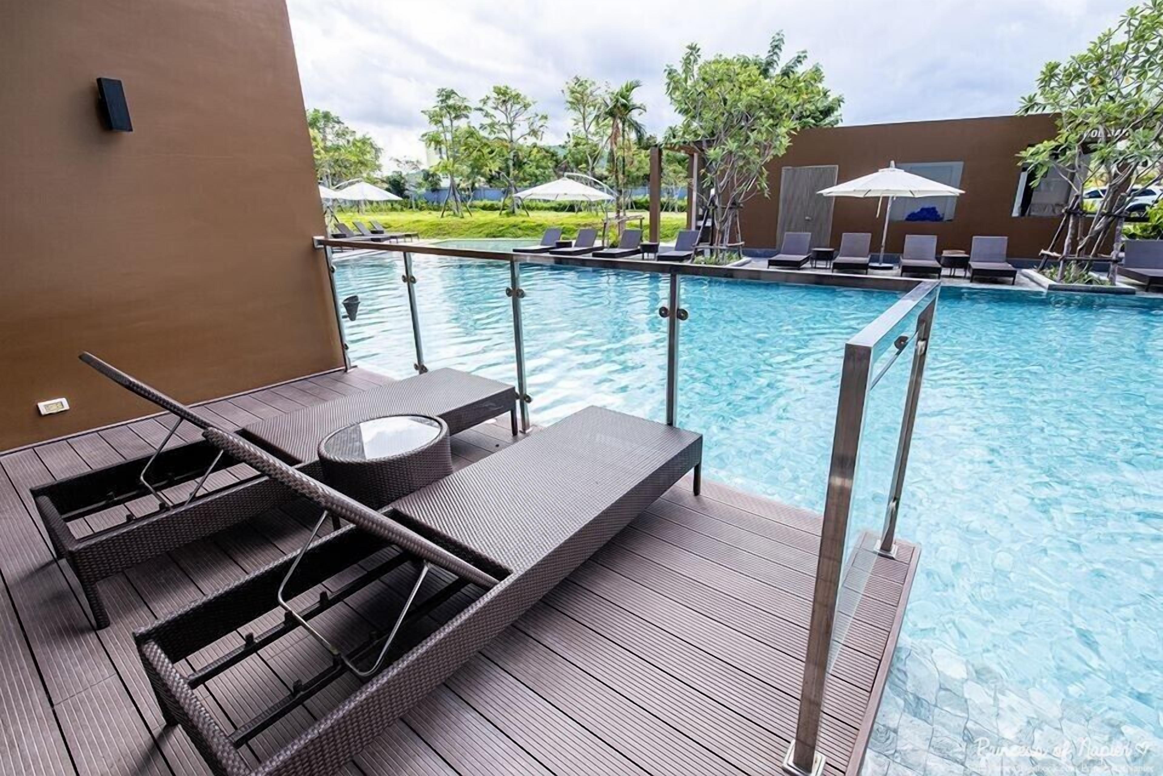 A poolside area with lounge chairs, a small table, and a wooden deck.