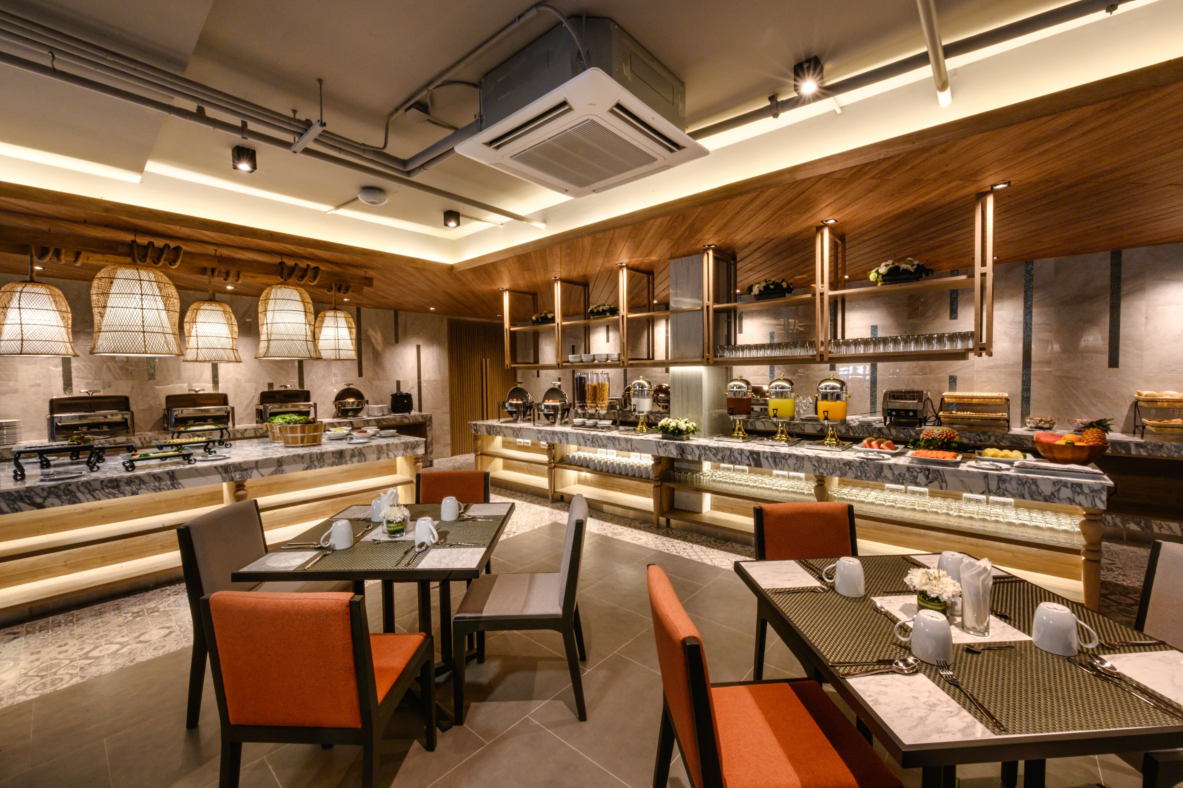 A modern restaurant with marble countertops, wooden accents, and a variety of dining options including a buffet area.
