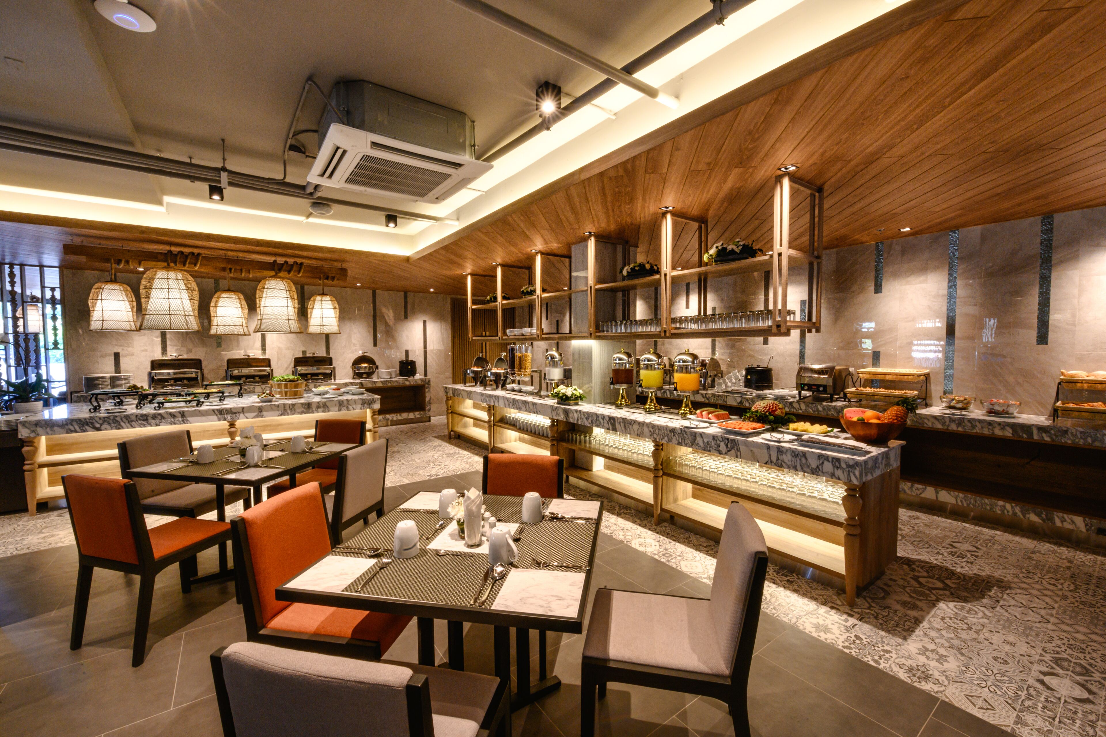 Un restaurant moderne doté d’un îlot central, de plusieurs espaces de restauration et d’une cuisine visible au fond de la salle.