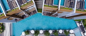 Um hotel moderno com uma grande piscina no terraço, várias varandas e áreas de estar ao ar livre.