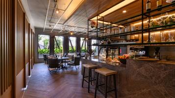 A modern bar area with wooden flooring, bar stools, and a wine display.
