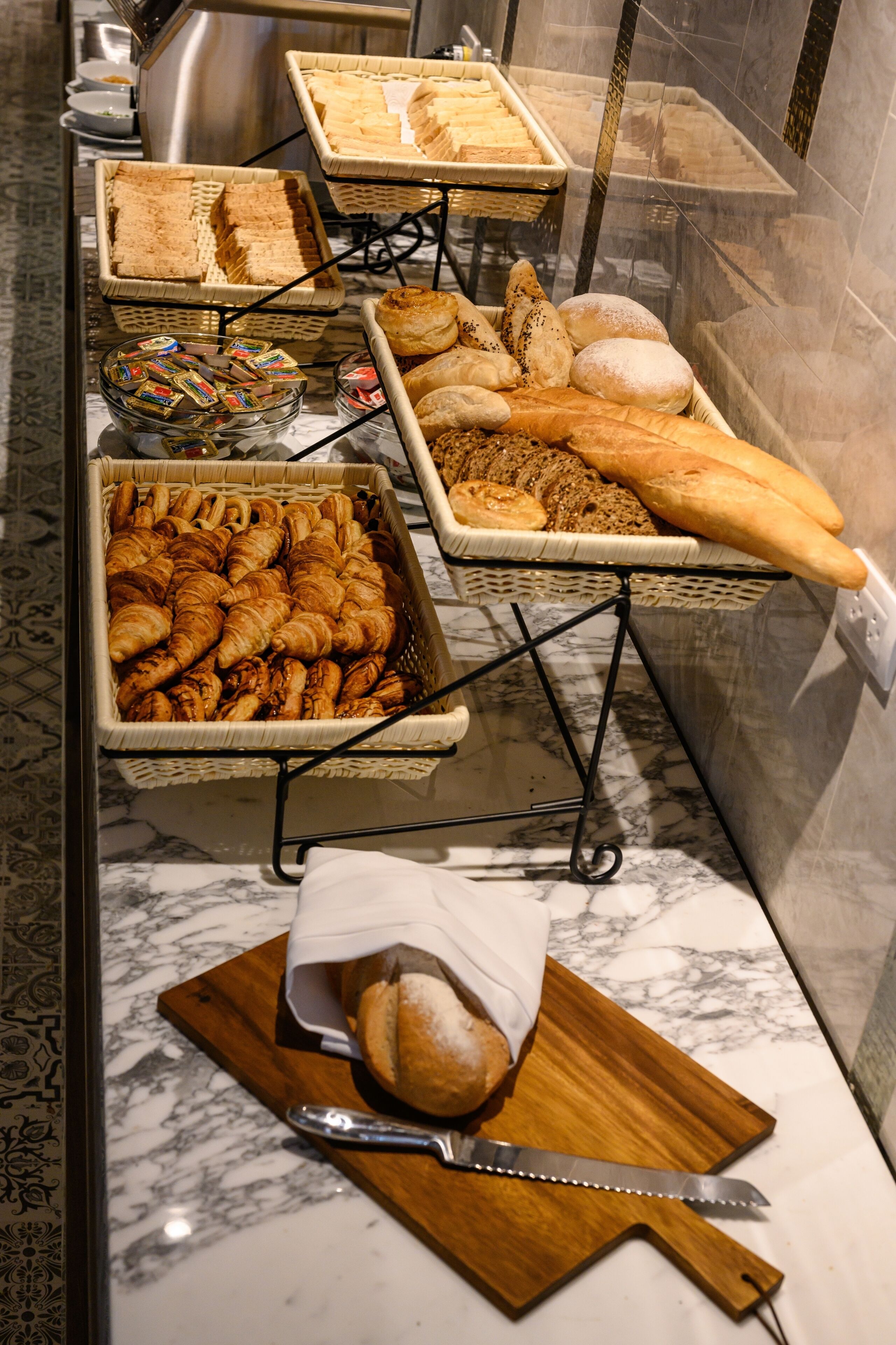 A buffet with various breads and pastries displayed on stands.