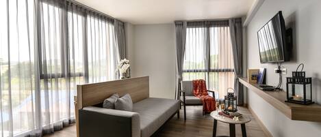 A modern living room with a sofa, a chair, a small table, and a TV mounted on the wall.