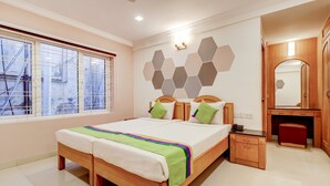 A hotel room with a large bed, a wooden wardrobe, a mirror, and a window with a view of the outside. - Treebo Terminus, Koramangala 5th Block (Bengaluru)