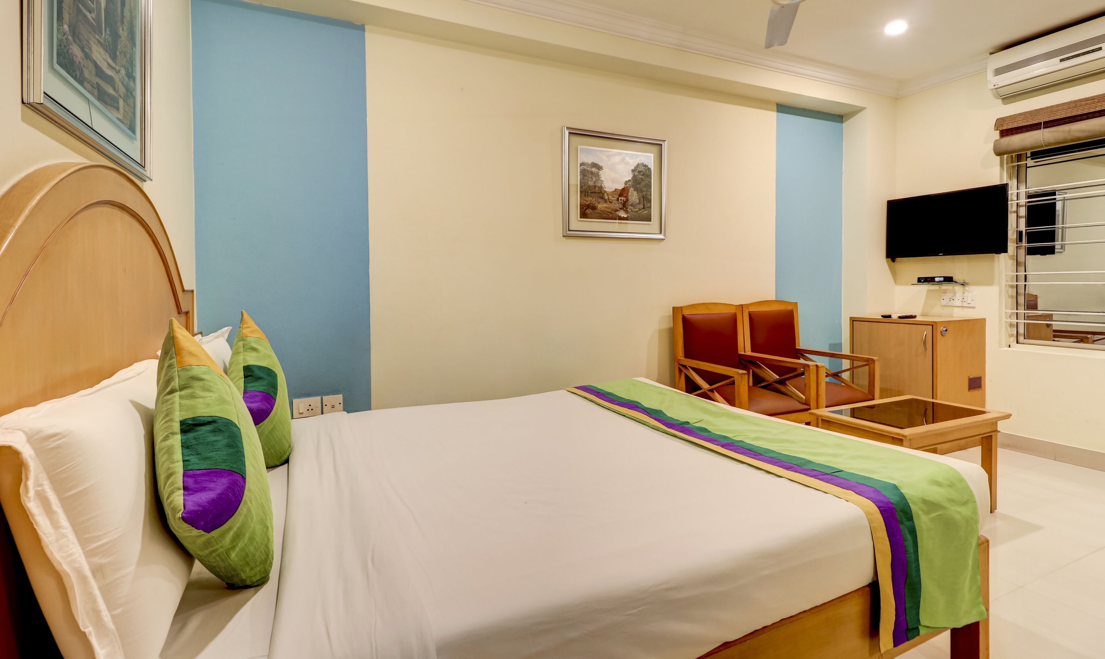 A hotel room with a bed, a chair, a desk, and a television.