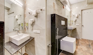 A modern bathroom with a white sink, a glass-enclosed shower, and a black marble accent wall.