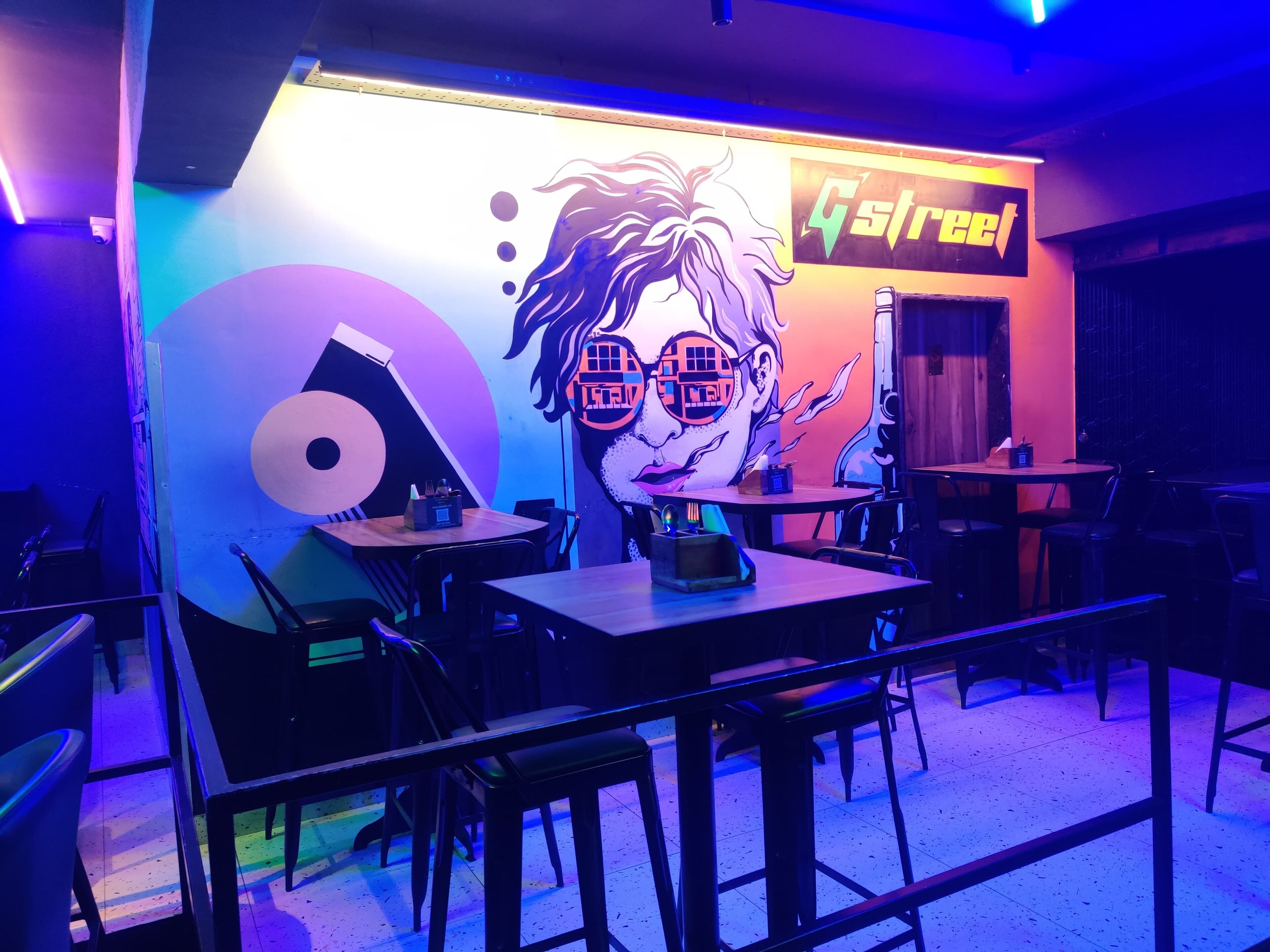 A restaurant interior with tables, chairs, and a mural on the wall.
