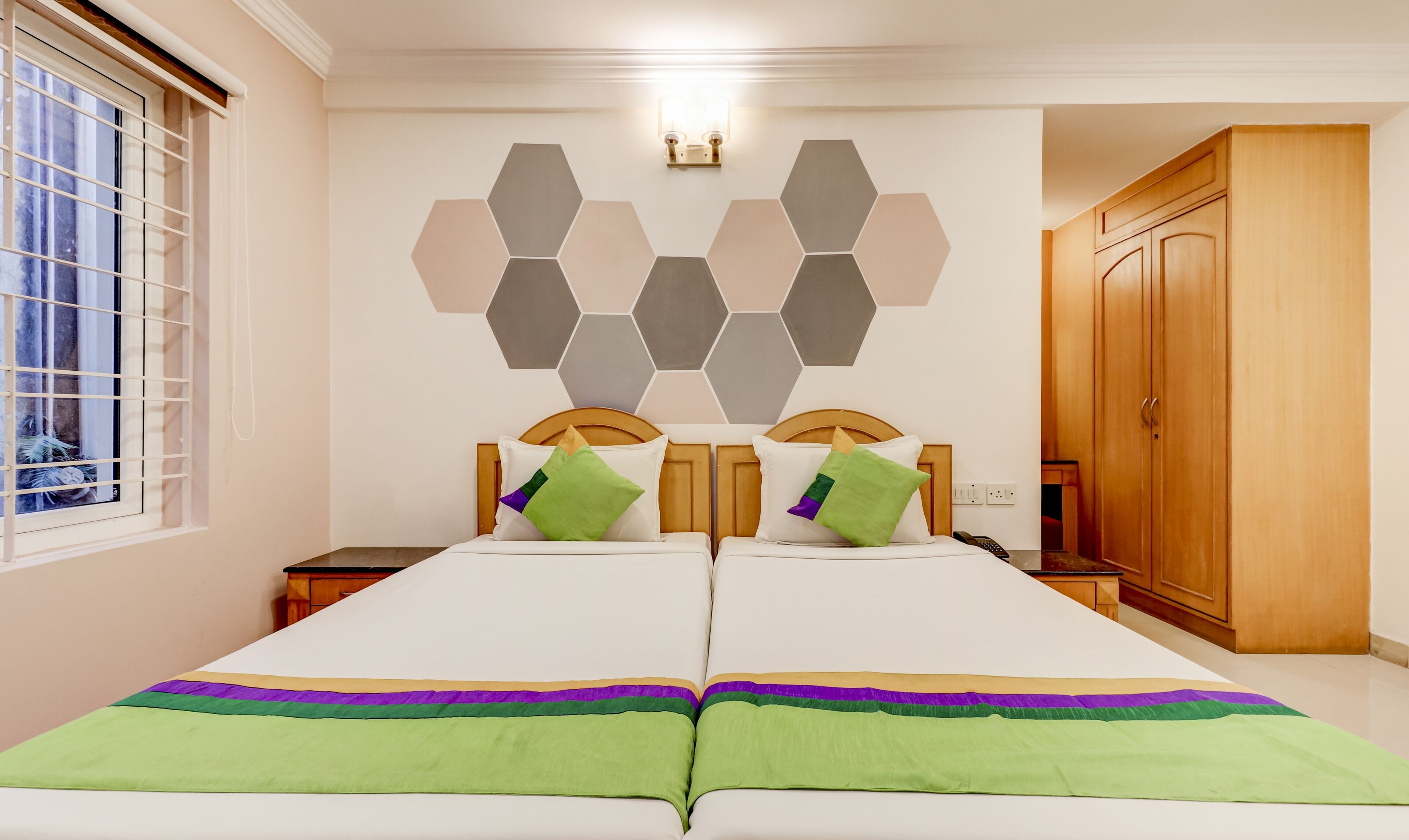 Un lit double avec deux tables de chevet, une armoire en bois et un élément de décoration murale de forme hexagonale.