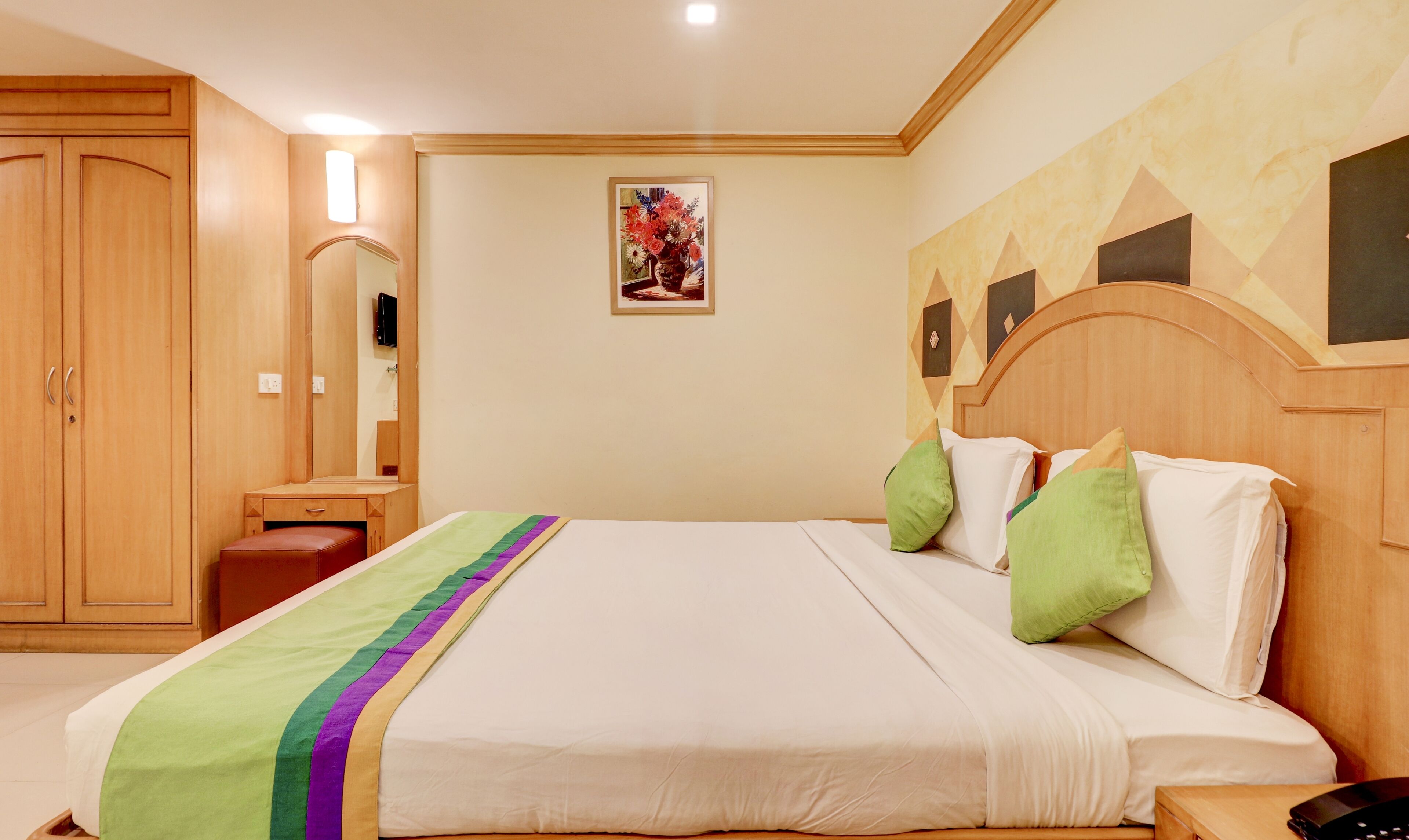 Habitación de hotel con una cama grande, un armario de madera y un espejo.