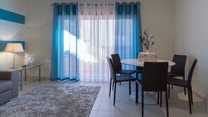 Uma sala de jantar moderna com uma mesa redonda, quatro cadeiras, uma mesa de centro de vidro e um vaso decorativo.